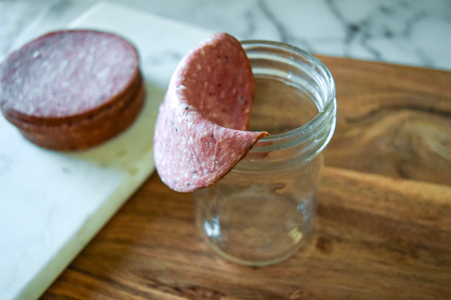 Salami Rose Step 1: Use a mason jar or glass cup place a slice of salami folded over the edge of the glass.