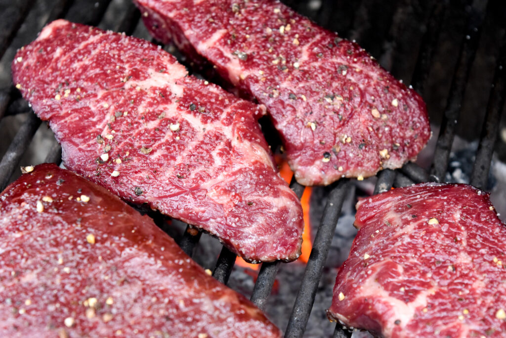 Denver steaks over a charcoal grill